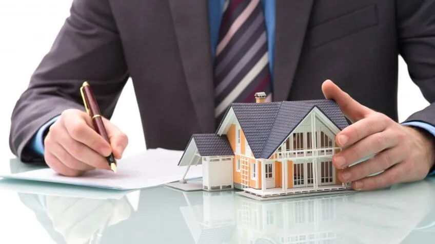 man holding toy house signing documents