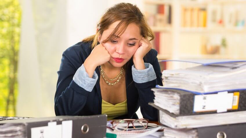 woman looking bored around binders and papers