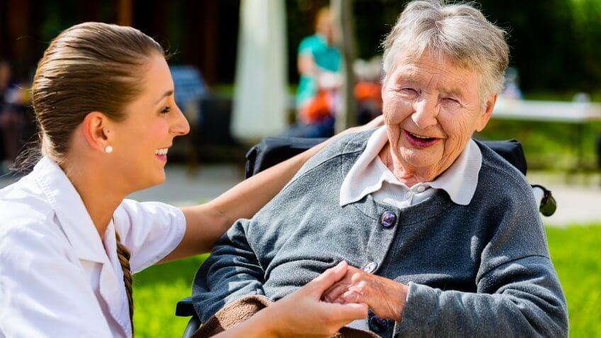 senior care young woman talking to a retired old woman
