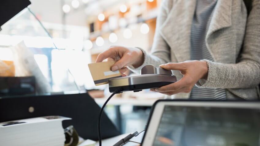 Customer paying at credit card reader in market.