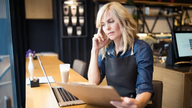 Coffee shop owner working on laptop.