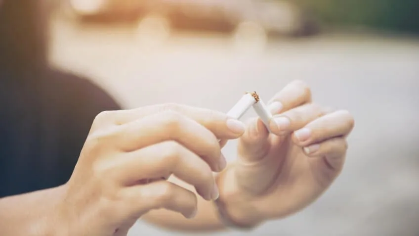 person snapping their cigarette in half