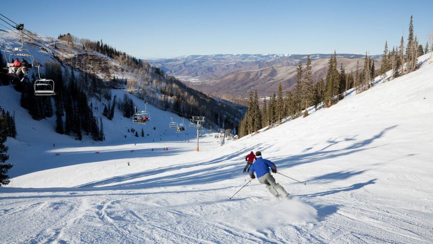 A pair of fast skiers rocket down a groomed trail on Ajax Mountain at Aspen Colorado.