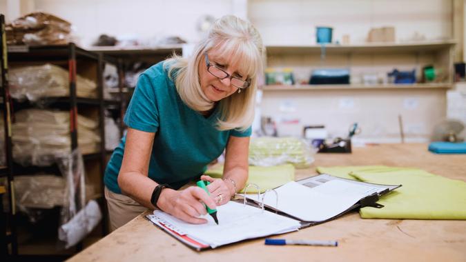 Senior businesswoman is doing paperwork in her stock factory.