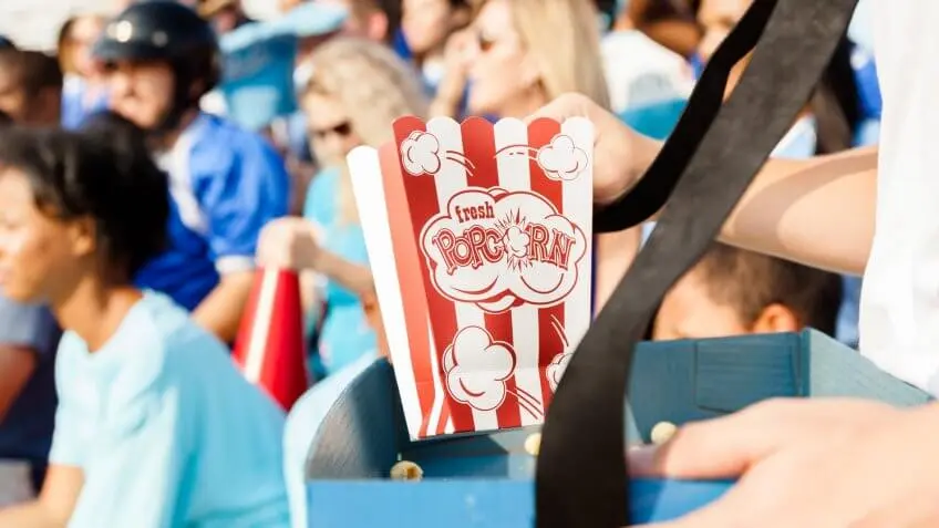 person handing out box of popcorn