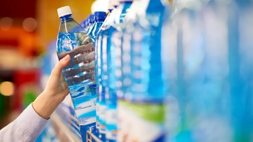 person pulling a plastic water bottle from shelf