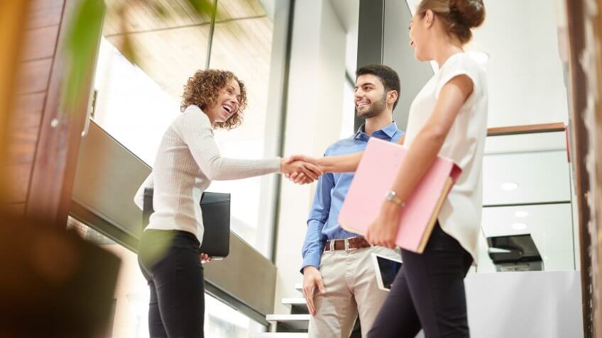three business associates say goodbye or hello at the door of a modern office.