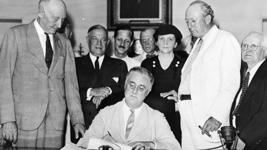 Roosevelt signs Social Security Bill.