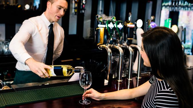 Barman serving a glass of wine in a bar.