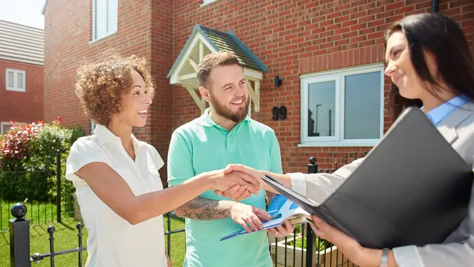 Couple discussing property options with a realtor, exploring opportunities to buy land or a house.