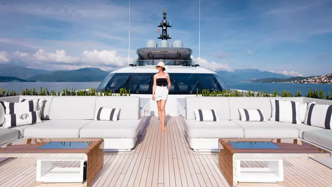A wealthy woman standing on an expansive yacht