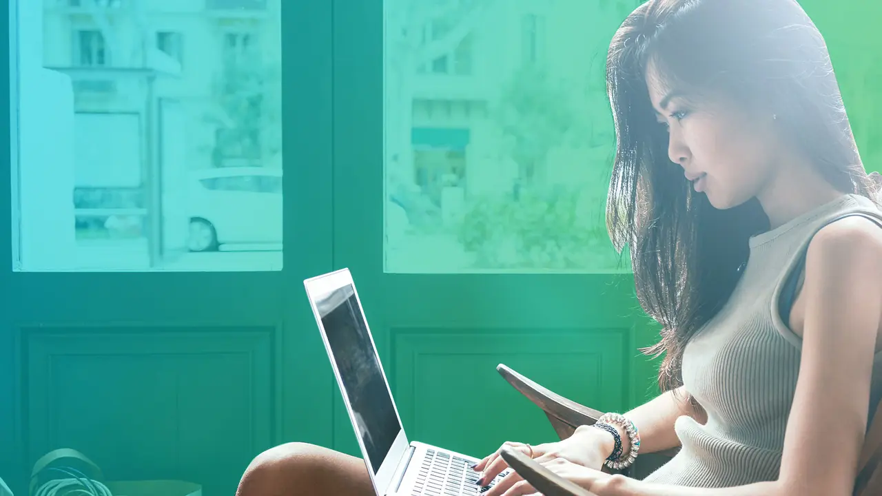 A woman sitting on a chair and looking at her laptop.