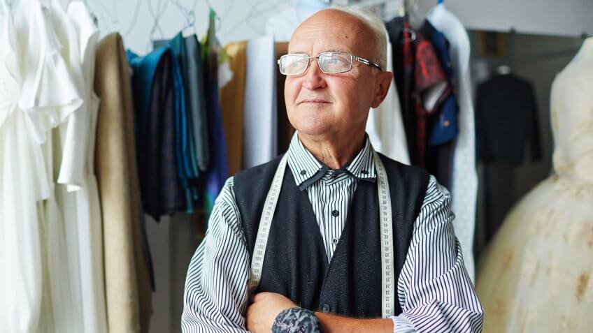 Senior tailor with measuring tape and needle-case.