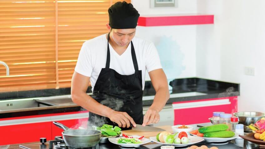 22 Industries That Pay Less (and More) Than They Did 10 Years Ag, Private Thai chef cooking in a modern style home kitchen. Making