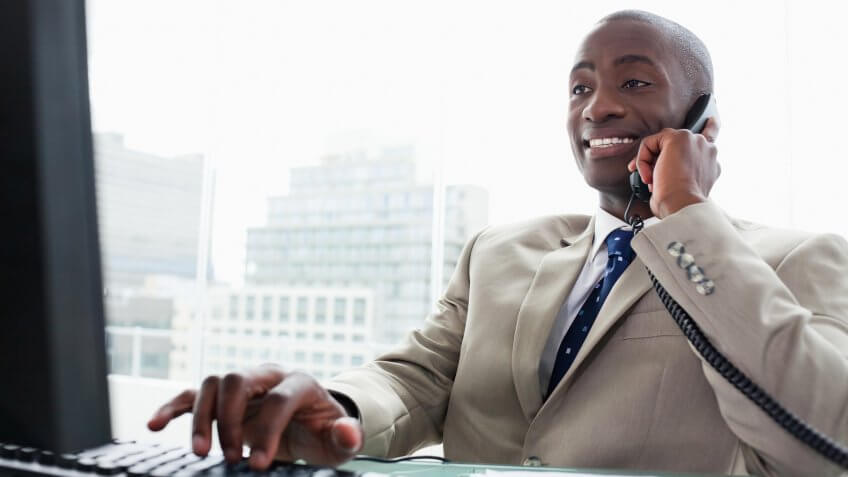 22 Industries That Pay Less (and More) Than They Did 10 Years Ag, Businessman on the phone while using a computer in his office