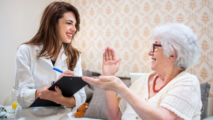 22 Industries That Pay Less (and More) Than They Did 10 Years Ag, Senior woman is visited by her healthcare worker at home.