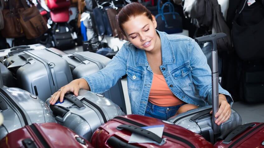 Smiling teenager girl choosing new large plastic luggage bag in , The Best and Worst Things to Buy in August 2017