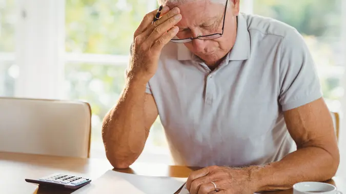 Secrets About Retiring That No One Wants to Talk About, Worried senior man with tax documents at home