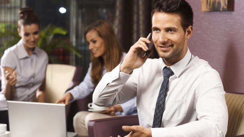 Free Hotel Upgrades That You're Missing Out On, Happy businessman talking on mobilephone, sitting in hotel lobby.