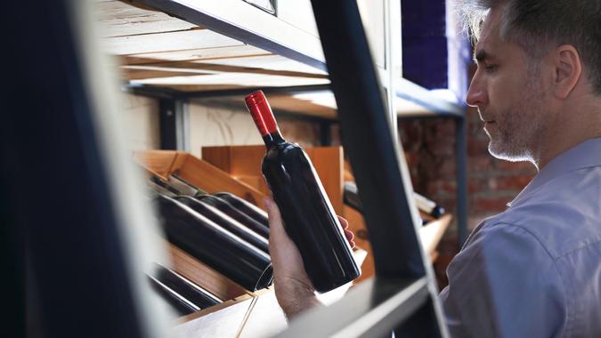 16 Most Important Assets That Will Increase Your Net Worth, Wine cellar.Wine cellar. Wine collection. Man chooses aging wine