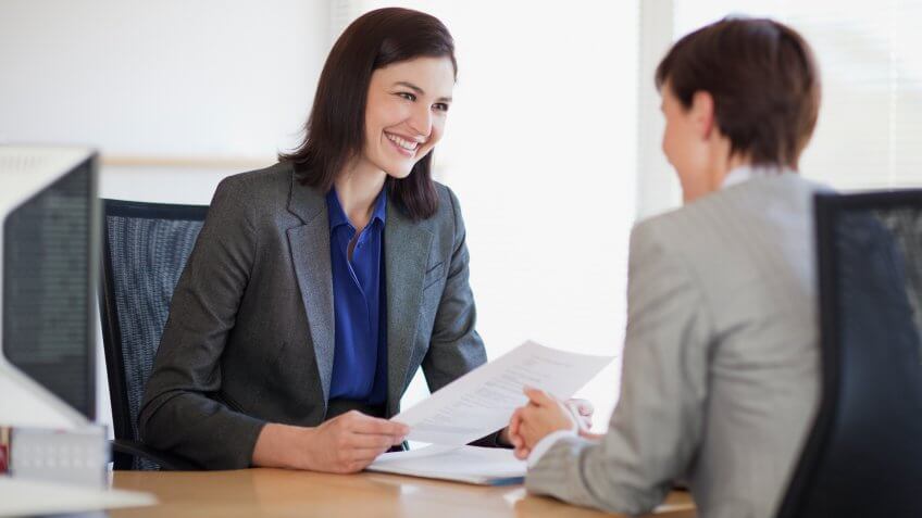 Businesswomen with paperwork talking face to face.