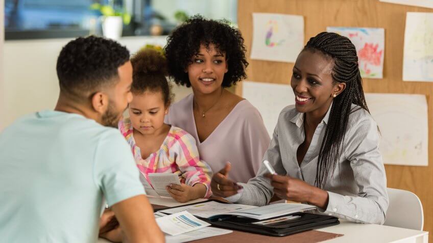 Financial advisor discussing bank details with young couple at home.