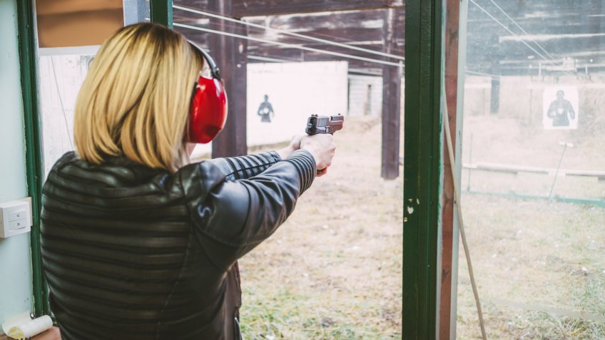 96 Money-Making Skills You Can Learn in Less Than a Year, Woman firing with pistol on target at the shooting range. Rear v