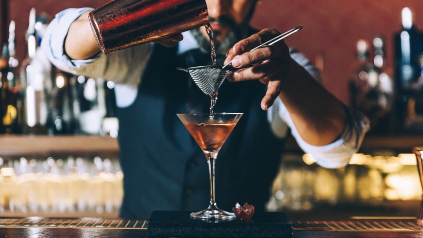 96 Money-Making Skills You Can Learn in Less Than a Year, Expert barman is making cocktail at night club.