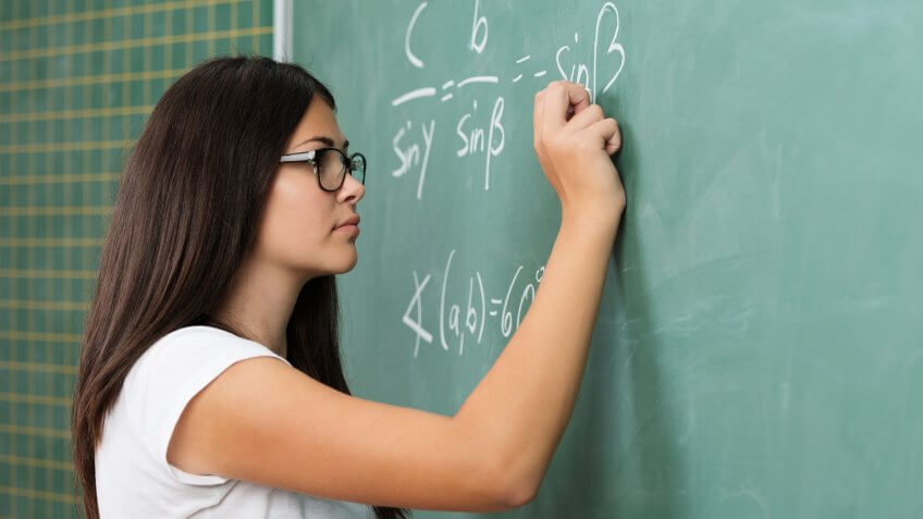 96 Money-Making Skills You Can Learn in Less Than a Year, Young female teacher or student wearing glasses standing at the