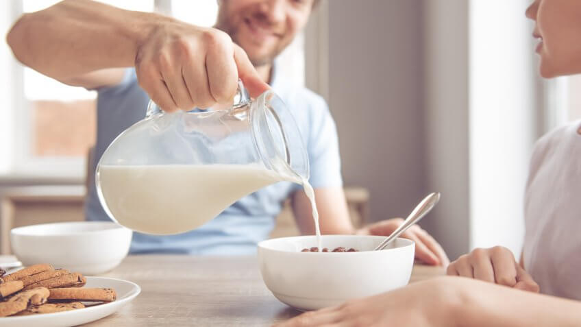 man pouring milk into bowl of cereal