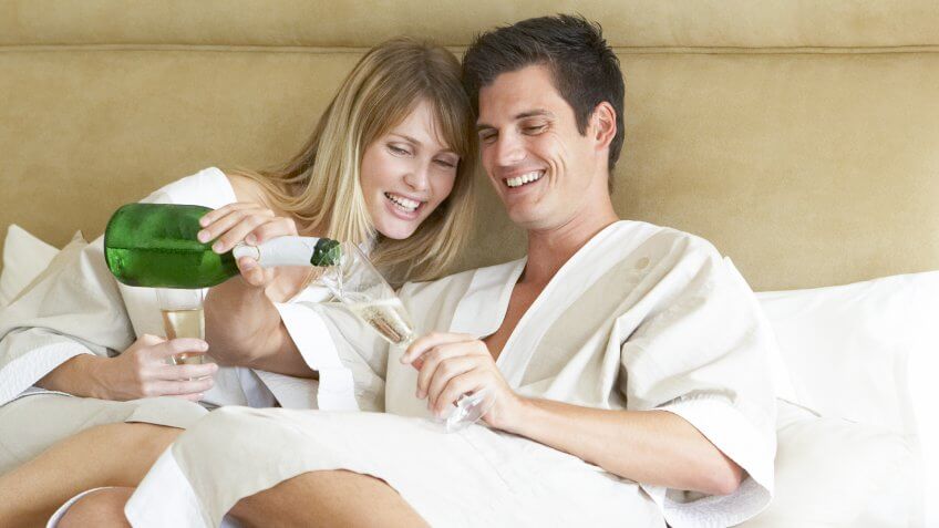 Free Hotel Upgrades That You're Missing Out On, Young Couple Enjoying Champagne In Bedroom