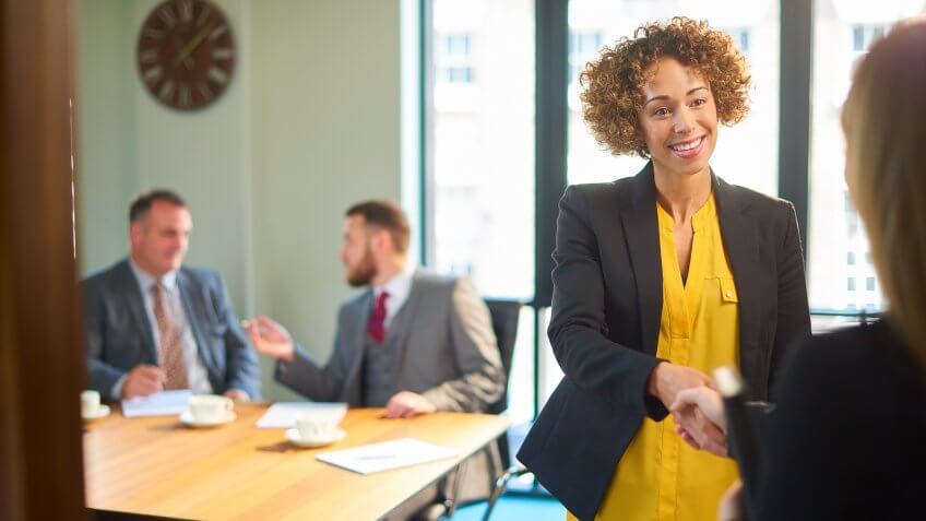 a member of an interview panel greets the next candidate for the job.