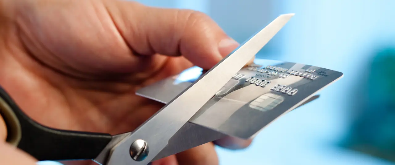 Scissors cutting a credit card on blue background.