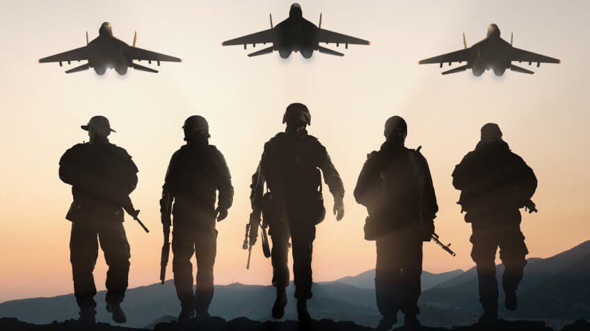 Military silhouettes of soldiers and airforce against the backdrop of sunset sky.