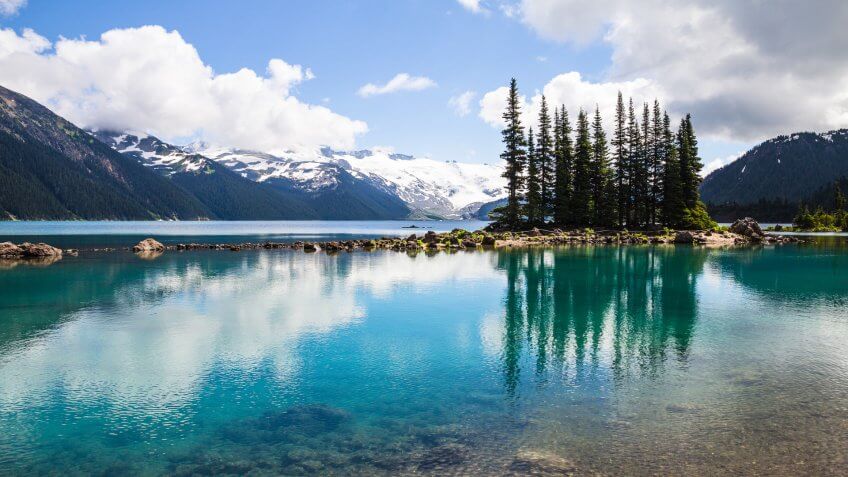 The clear, tranquil waters of Garibaldi Lake in Garibaldi Provincial Park near Whistler in British Columbia, produce bottle-green reflections of an island of conifers.