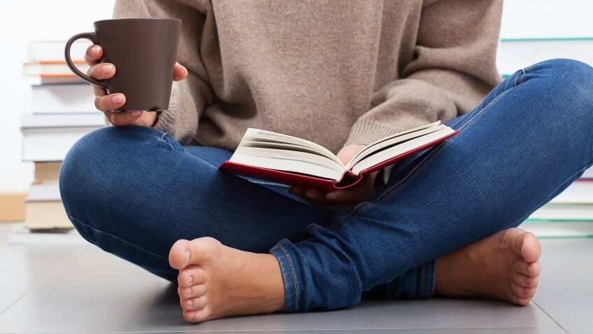 Woman sitting on a floor and reading a book.