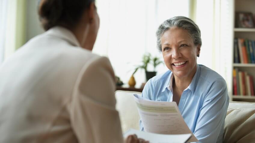 Hispanic saleswoman talking to client in living room.