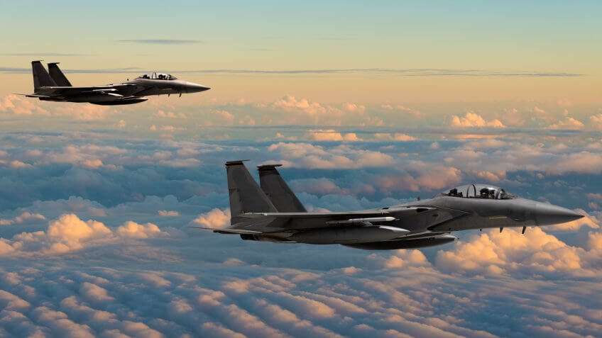 F-15 Eagle fighter jets flying above clouds.