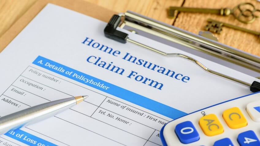 Blue ballpoint pen, Secret Tips to Live a Financially Secure Life, two antique brass keys and a home insurance claim from on a plyw