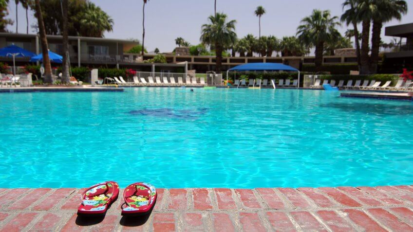 "Sandals Next To Large Empty Swimming Pool In Palm Springs, California".
