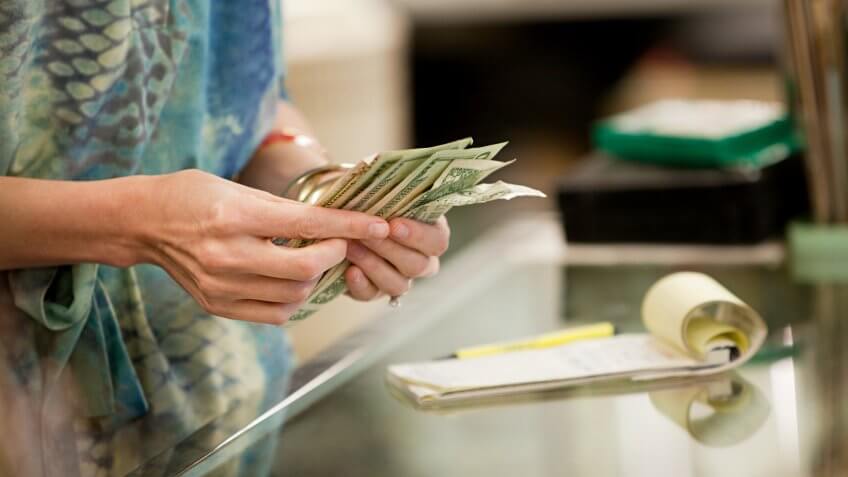 Shop keeper counting money in shop.