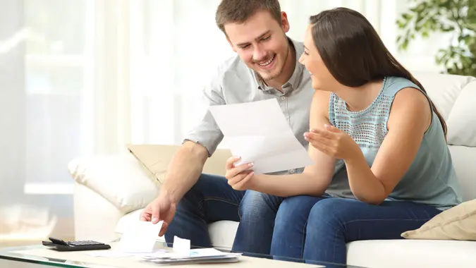 Happy couple reading mail and checking accountancy looking each , Secret Tips to Live a Financially Secure Life