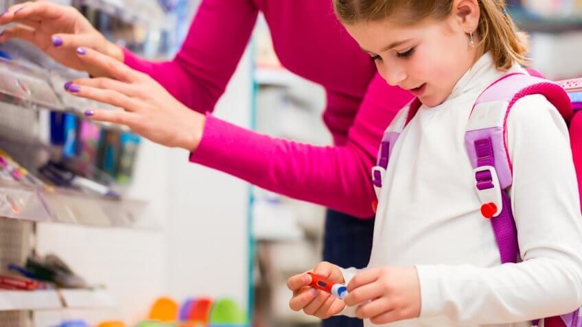 Family buying school supplies in stationery store, little girl looking at a fountain pen.
