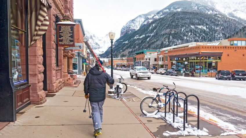 Skier Walks the Streets of Telluride, Colorado With His Skis, Boots, and Poles.
