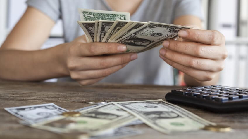Close up of woman with calculator counting money.