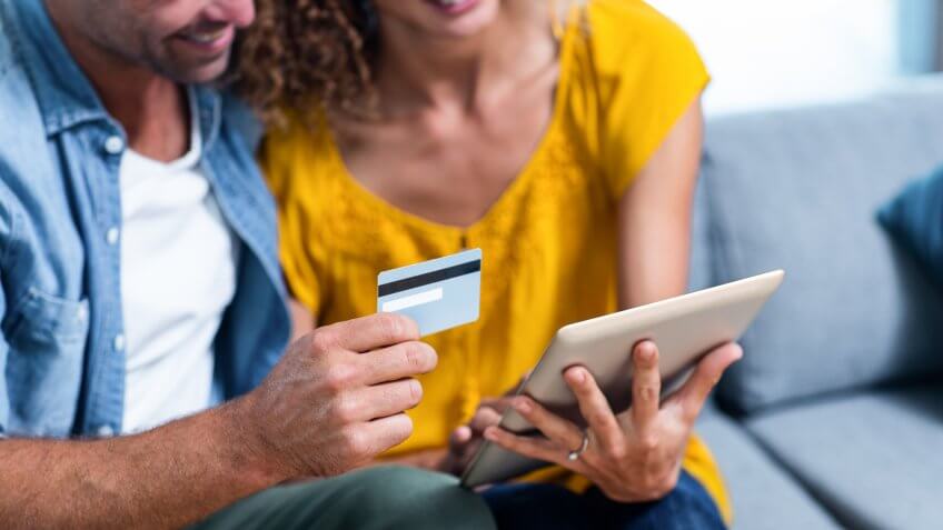 man holding credit card while woman holds tablet