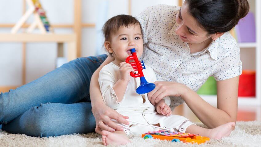 baby and her mother play musical toys.