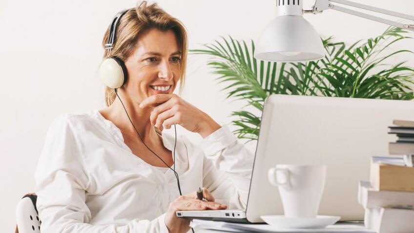 Smiling mature woman listening music with headphones.