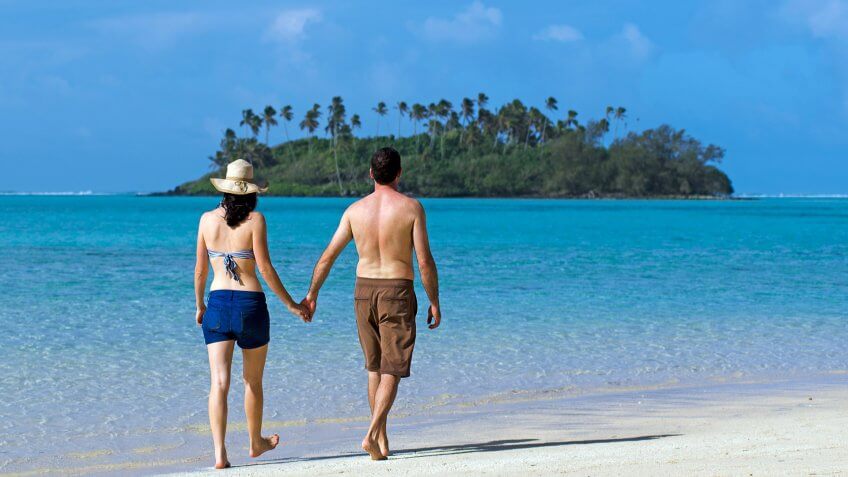 Attractive young happy couple on vacation walks on a beach of Pacific Island.