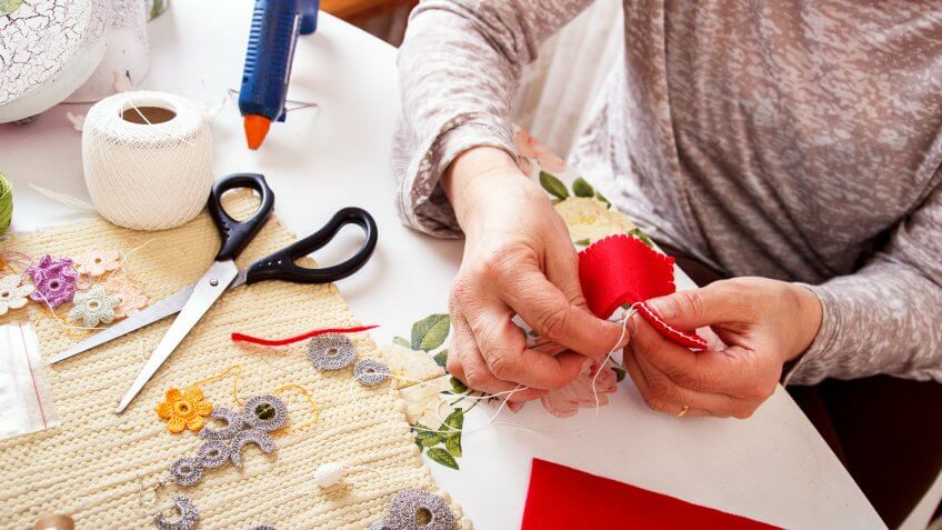 Senior women sews by hand and making owl shape ornament.